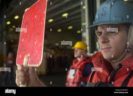 US Navy Seaman flashes the hold signal board during a replenishment at sea  Stock Photo