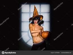 Woman in witch halloween costume with hat standing over night light  background. Beautiful naked woman in witches hat and halloween costume.  Halloween, holidays celebration. Stock Photo by ©Tverdohlib.com 222350060