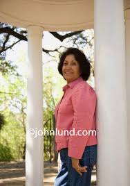 Mexican women can be petite with tanned skin and long dark hair; Happy Senior Latina Woman Smiling And Standing On A Porch