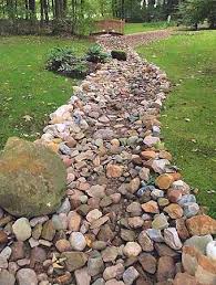 At times the drain accumulates leaves and this slows the drainage, but it still works. Dry Stream Beds For Drainage Or Design Dry Stream Beds Create The Look Of A Stream Without River Rock Landscaping Landscaping With Rocks Backyard Landscaping