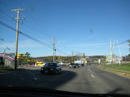 The scene unfolds at the side of a road, where a silver car is parked outside of what appears to be a convenience store. Road Trip