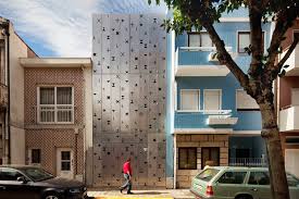 Bar grating used as an entry door and facade element filters the light entering the space behind and provides privacy. House 77 Is An Urban Loft With A Funky Perforated Aluminum Facade