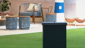 Decoração de área externa com poltrona azul, tambores decorativos, farol e gramado artificial.