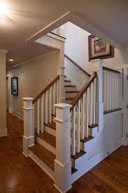 This second floor landing has a stylish hardwood flooring that leads to the home's hallway with a tiles flooring and a pendant lighting. L Shaped Stair With Painted Balusters And Risers And Stained Treads And Hand Rail Staircase Design Craftsman Staircase Staircase Remodel