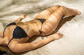 Nua Mulher Bonita Nudista Em Chapéu De Palha Deitado E Banhos De Sol Em Uma  Sombra Sob Ramos De Palmeira. Relaxamento Feminino Na Praia De Areia Em  Férias De Verão. Vista Superior