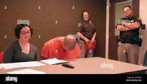 Sean Riker breaks out laughing and puts his head down when it is alleged  that he threated to kill his children. He was ordered held