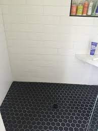 We love how this bathroom committed to white tiles paired with black grout but didn't get stuck using a single style. Black Hex Shower Floor With Oversize White Matte Subway Tile Shower Tile Black Floor Tiles Shower Tile Designs