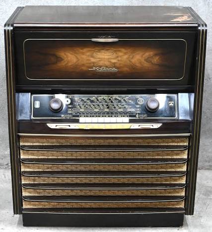 Grundig Konzertschrank 7063/56. Een vintage radio -en platenspeler meubel, in werkende staat. Lichte schade bovenblad. Bijgevoegd 40-tal bakelieten 75-toeren platen, waaronder OLV toren – La Esterella. – Jordaens N.V. Veilinghuis