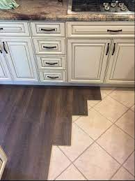 Since laminate flooring has a photograph on its top, you can achieve the look of a hardwood floor in your bathroom just by laying it over tile. Coretec Installed Over Tile My New Love Affair Diy Kitchen Flooring Tile Floor Diy Kitchen Floor Tile
