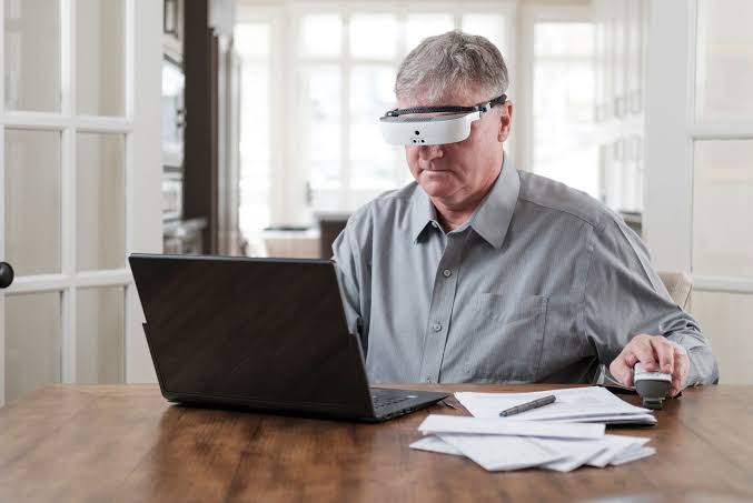 eSight elektronik gözlüğünü kullanan bir kişinin bilgisayar ekranını rahatlıkla incelemesini gösteren temsili görsel
