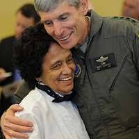 An elderly man in a wheel chair being assisted by a nurse. Hospice caring  for elder help.