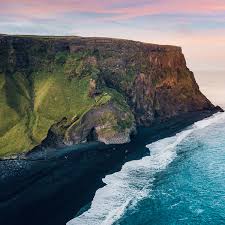 This is a photo of where green fields, yellow river, black beach and blue sea meet in iceland. Reynisfjara Black Sand Beach In Iceland Complete Travel Guide Adventures Com