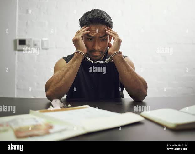 Man, criminal and handcuffs in fear for interrogation, drugs or crime in  arrest on table in room. Worried male person, gangster or suspect in jail  Stock Photo - Alamy