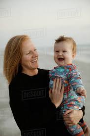 Single Mom With Red Hair Holds Laughing Chubby Baby Boy On The Beach Stock Photo Dissolve