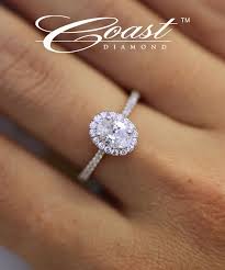 An Elegant Engagement Ring Featuring An Oval Diamond Halo And Delicately Set Diamonds On The Sh Elegant Engagement Rings Engagement Rings Unique Bridal Jewelry