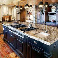 Kitchen island cooktop featuring a stainless steel hood flanked by rustic small wood beams above clear glass lanterns hung over a dark brown kitchen island fitted with a gas integrated cooktop fixed to a white quartz countertop seating. Marble Countertops Pros Cons And Some Alternatives Kitchen Island With Sink Kitchen Island With Cooktop Kitchen Island With Stove