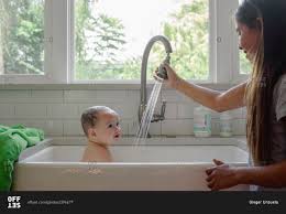 Rinse by pouring a cup of warm water over your hair. Young Girl Giving Baby A Bath In Kitchen Sink Stock Photo Offset