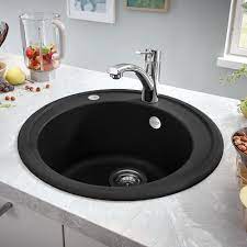 Dark countertops and white cabinets get a boost of color from a teal farmhouse sink and backsplash. Trending Black Kitchen Sinks Victorian Plumbing