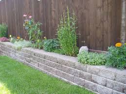 Once a few rows have been stacked, backfill the wall with rock so it matches the grade height in front of the wall, and then lay down perforated drain tile on top of the rock. Planters Patiotown Com Backyard Retaining Walls Diy Backyard Patio Planter Boxes