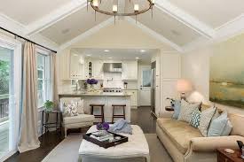 This living space shows large square tile flooring, a small accent rug in front of a sectional and red brick wood burning fireplace. Living Room Cathedral Ceiling With White Wood Beams Transitional Living Room
