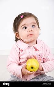Thinking Baby Girl Holding An Apple In Her Hands And Looking Away Stock Photo Alamy