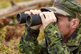 Young Soldier or Hunter with Binocular in Forest Stock Photo