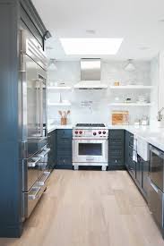 U Shaped Blue And White Kitchen Boasts Blue Kitchen Cabinets Accented With White Quartz Countert Galley Style Kitchen Mid Century Modern Kitchen Kitchen Design