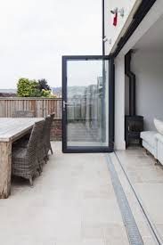 Aluminium Bi Fold Doors Level Threshold With Stone Floor Seamlessly Connecting Inside And Outside Spaces Con Patio Flooring House Exterior Outside Flooring