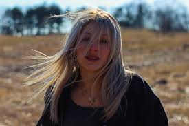 A woman with blonde hair standing in a field photo