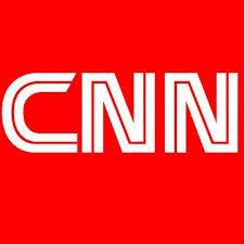 Cnn logo on the tablet screen laying on the white table with scattered popcorn and apple earphones. Cnn Logo Cnn Logo Twitter