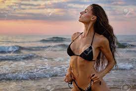 Slim Millennial Woman In Black Bikini Pose On Beach Near Sea. Beauty  Fashion, Travel And Vacation Summer Holidays. Sexy Girls With Perfect Body  And Summertime Collection, Fitness Bikini Model Concept Фотография,  картинки,