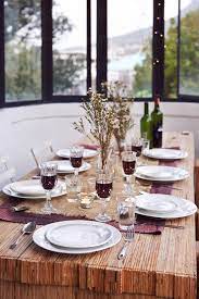 Elegant glass top dining room table setup with six place settings for a dinner party with white cloth napkins and wine goblets. Casual Table Setting For House Party By Jill Chen