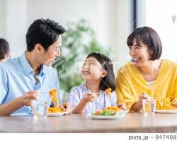 笑顔で食事をする親子の画像