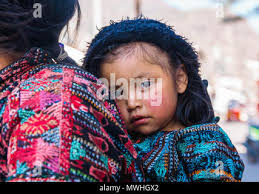 An hispanic girl in a floral dress opens her Easter basket Stock Photo