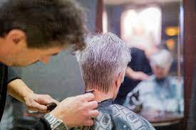 Ältere Frau bekommt neuen Haarschnitt, Friseurin rasiert sich den Nacken,  lizenzfreies Stockfoto