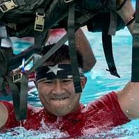 An Airman jumps into a pool during a water survival