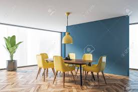 Stylish yellow and gray dining space features fornasetti plates hung from a gray wall beside a window dressed in white curtains and behind a wood dining table with yellow dining chairs. Corner Of Modern Dining Room With Blue Walls Wooden Floor Long Dining Table With Yellow Chairs And Industrial Style Lamp 3d Rendering Stock Photo Picture And Royalty Free Image Image 138604056