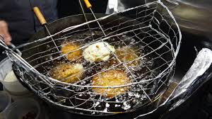 Fuzhou oyster cakes deep-frying in hot oil at a heritage hawker stall in Maxwell Food Centre Singapore