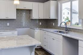 White Cabinets Quartz Countertops And Grey Glass Tile Backsplash Glass Backsplash Kitchen Trendy Kitchen Backsplash Kitchen Remodel