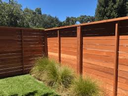 When building a fence on uneven terrain, one option is to follow the contours of your yard. Redwood Fencing Style Choices From A And J Fencing
