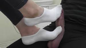 Mes pieds en chaussettes blanches jouent avec la bite et les couilles