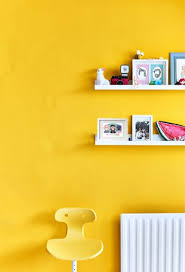 A Yellow Chair Against A Yellow Wall With Shelves House Colors Colorful Furniture Yellow Walls