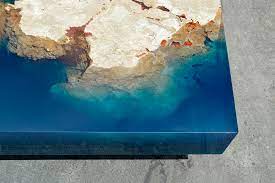 The table smooth and colourful surface is achieved by pouring coloured epoxy onto the uneven surface of the wooden table. New Cut Stone Tables Encased In Resin Mimic An Ocean Reef Colossal
