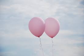 two pink balloons under white clouds
