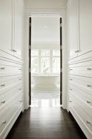 Long Narrow Walk Through Closet Features Floor To Ceiling Built In Cabinets Atop Dark Stained Oak Wood Floors Home Walk Through Closet Remodel Bedroom