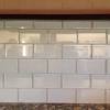 The backsplash contains trimmed, rectangular tiles that are ordered in skewed. 1