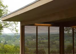 The side wall features horizontal wooden shutters that emphasise the natural, authentic design and ensure plenty of protection from the elements. Modern Outdoor Lloyd Hamilton