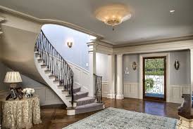 Blue dining room with stairs, round table. Classic Entry Spiral Staircase Skirted Round Table The Glam Pad