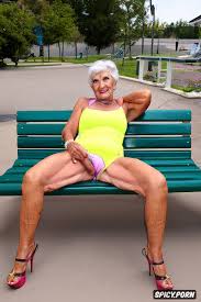 Image of old skinny beautiful wrinkled granny tongue out in detailed  spandex yellow short shorts lips cameltoe spread leg sit on bench outside  in hot summer showin pussy bulge point of view -