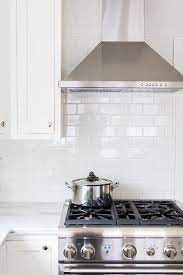 Beautiful White Kitchen Features A Stainless Steel Hood Mounted To An All White Subw Kitchen Backsplash Designs White Kitchen Backsplash Tin Backsplash Kitchen